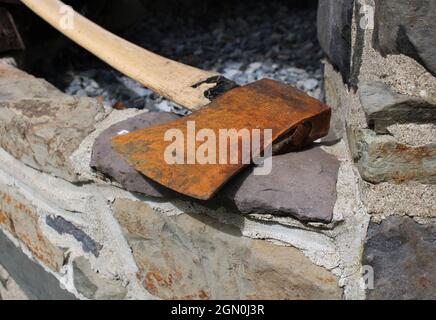 An Old Rusty Axe on a Stone Ledge Stock Photo