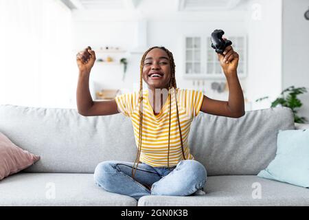Emotional young black woman winner playing video games at home Stock Photo