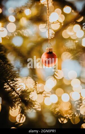 red bauble hangs on the illuminated Christmas tree, Christmas, family Stock Photo