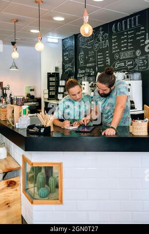 Owners of a coffee shop working looking at the tablet Stock Photo