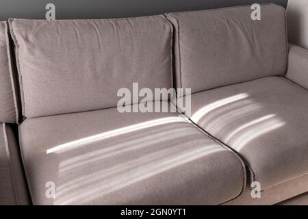 Wide sofa with sunlight pattern on it, abstract blank interior fragment Stock Photo