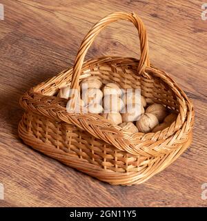 wicker basket with walnuts stands on the floor in the room close-up Stock Photo