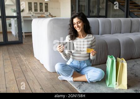 Millennial Caucasian lady with tablet pc using credit card while shopping online from home, blank space Stock Photo