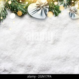 Christmas background, green pine branches, gift box on snow background and light. Creative composition with border and copy space, top view. New Year' Stock Photo