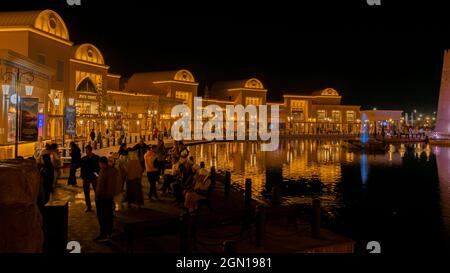 Tourists by water channel in Karavan-Saray, a multifunctional tourist complex attraction, lit up at night; in historic city Turkistan, Kazakhstan Stock Photo