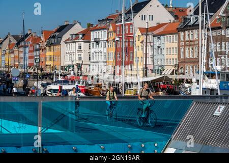 Cyclists on the Inderhavnsbroen cycle and footbridge, over the harbour, at Nyhavn, Copenhagen is considered the cycling capital of the world, 45% of t Stock Photo