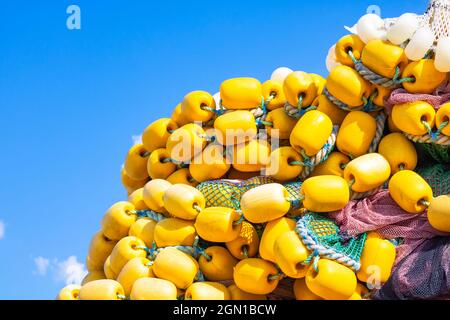 Heap of yellow fishing net floats on the blue sky background. fishing industry. Yellow fishing bobbers. Stock Photo