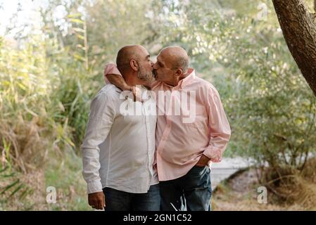 Gay mature couple kissing while enjoying romantic time together in a park. Stock Photo