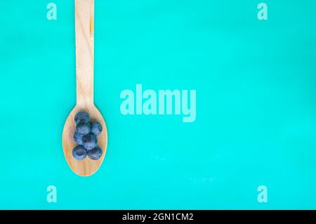 Flat lay of recycled spoon and juicy fresh blueberries on color table ...