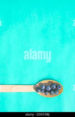 Flat lay of recycled spoon and juicy fresh blueberries on color table ...