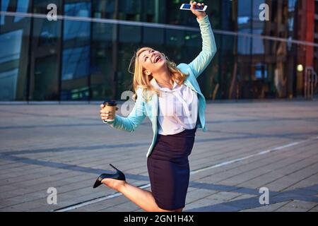 Happy expressive female manager is standing near office building. Stock Photo