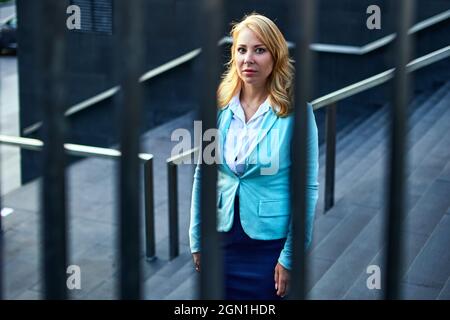 Depressive woman in business suit stands outside. Stock Photo