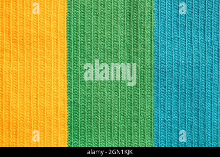 Eye-pleasing crochet pattern in three different soft colors yarn: yellow, green and blue cotton thread, symmetrical background created by the stitches Stock Photo
