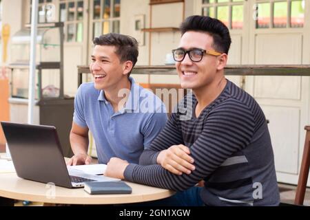 Two young adults laughing. Students at desk outdoors. Stock Photo