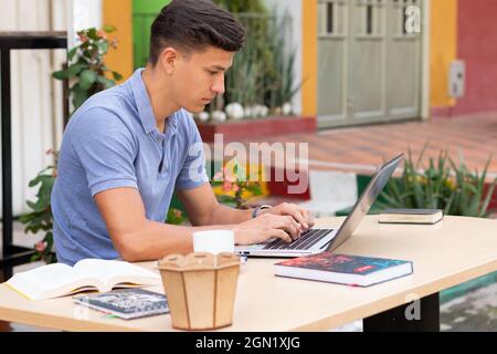 Young adult typing on his laptop and in his backyard. Stock Photo