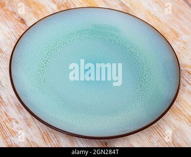 Blue ceramic plate with black edging on wooden background Stock Photo