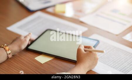 Closeup, Professional businesswomen using stylus pen and tablet with financial spreadsheet data report on table Stock Photo