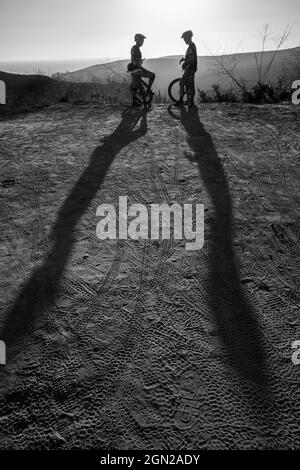 Laguna Beach, California, USA. 2nd Oct, 2019. Two mountain bikers in silhouette talk as a long shadow is cast on the ground in Laguna Coast Wilderness. (Credit Image: © Ruaridh Stewart/ZUMA Press Wire) Stock Photo