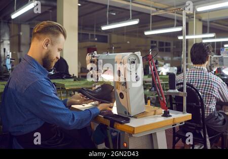 Craftsman shoe designer sewing boot on stitching machine side view shot Stock Photo