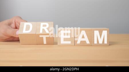 Dream team on wooden cubes. Hand is turning a dice and changes the word dream to team. Dream Team message. Business and dream team concept, copy space Stock Photo