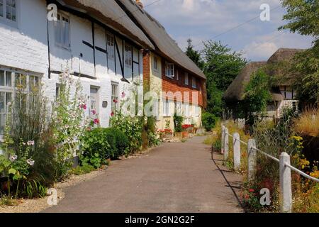 Half timbered houses with thatched rooves, a stream and colourful flowers in the pretty village of East Meon, Hampshire, England Stock Photo