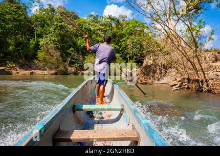 A panamanian man in a dugout canoe is travelling upwards Rio Pequeni, Chagres national park, Republic of Panama, Central America. Stock Photo