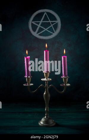 Candle magic. Purple candles in a vintage candleholder with a pentagram on a dark background Stock Photo