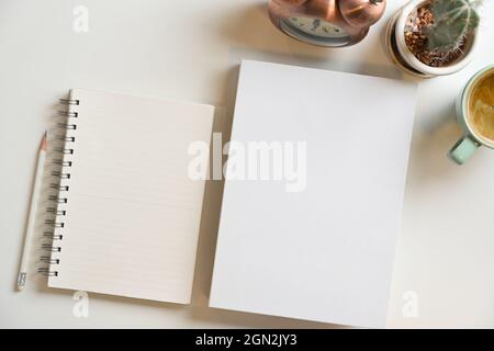 Blank book cover and notepads for text display on white background with vintage alarm clock, cactus, and coffee cup, View from the top Stock Photo