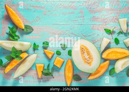 Healthy snack - Piel de sapo melon and cantaloupe with fresh mint on cyan wooden table Stock Photo