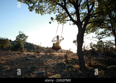 girl swinging freely in nature Stock Photo
