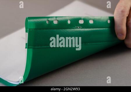 An adult male is holding a green file folder for papers. Person Stock Photo