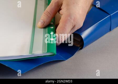 A mature male hand is holding a green file folder. Blue document Stock Photo