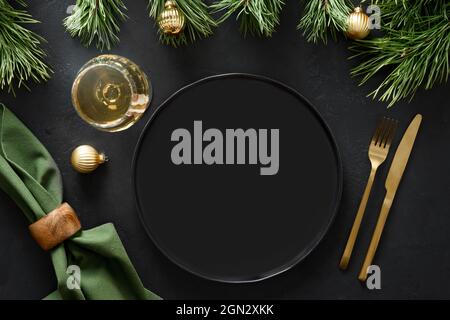 Christmas empty table setting with sparkling wine, golden cutlery and festive decorations on black background with copy space. Top view. Xmas or New Y Stock Photo