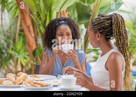 Two beautiful young adult African American women friends having a breakfast outside Stock Photo