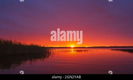 Red sunset over the lake with reflection in the water Stock Photo