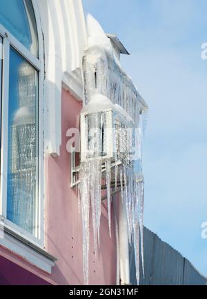 Air conditioner compressor in ice. Frozen house air conditioning with icicles outside. Stock Photo