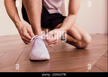 Close up of sporty senior man tying shoelaces on sneaker. Home workout. Stock Photo