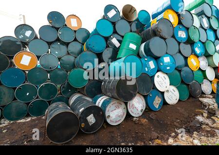 CHACHOENGSAO, THAILAND-JUNE 24, 2021 : Old chemical barrels stacked. Steel tank of plasticizer with label. Blue, green, black, and yellow chemicals Stock Photo