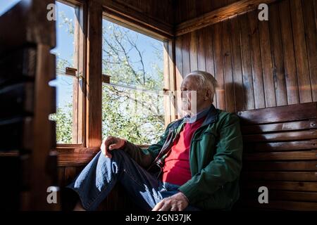 Attractive man and old man traveling in an old wooden train carriage looking out the window Stock Photo