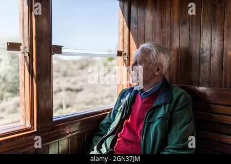 Attractive man and old man traveling in an old wooden train carriage looking out the window Stock Photo
