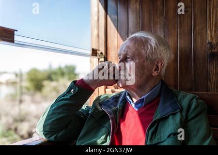 Side view of attractive man and old man traveling in an old wooden train carriage looking out the window Stock Photo