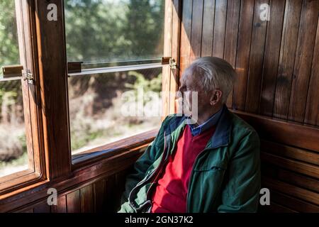 Attractive man and old man traveling in an old wooden train carriage looking out the window Stock Photo