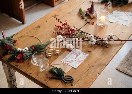 From above Christmas composition with colorful postcard with inscription Feliz Navidad placed near burning candles and cups of tea on wooden table dec Stock Photo