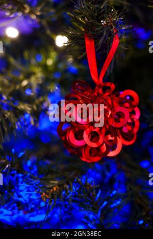 Festive ornament hanging on branch of coniferous tree decorated with garland for Christmas celebration Stock Photo