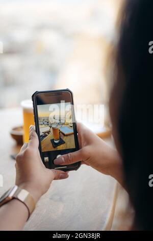Crop anonymous female customer taking picture with mobile phone of beer and snacks in bar Stock Photo