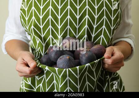 Woman holds fig in apron, front view Stock Photo