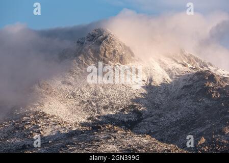 Mountain slope covered with snow and clouds in cold winter day in Sierra de Guadarrama National Park Stock Photo