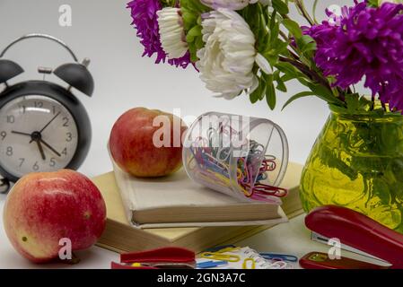 A composition of flowers in a vase, books and various educational accessories on a light background. Congratulations on the teacher's day. Stock Photo