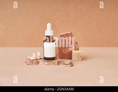 Small bottle of beauty oil and natural handmade soap pieces with pumice stone on two color background Stock Photo