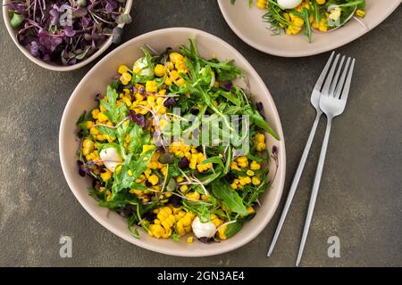 Salad with young boiled corn and mozzarella cheese, arugula and microgreen radish, fresh summer salad, top view Stock Photo